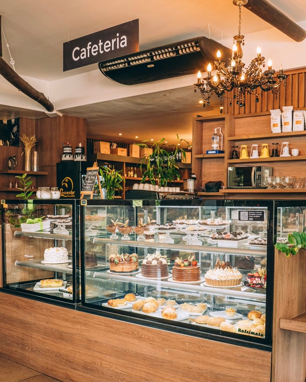 Balcão da Cafeteria Marquês com vitrine de doces e tortas sob luz de lustre