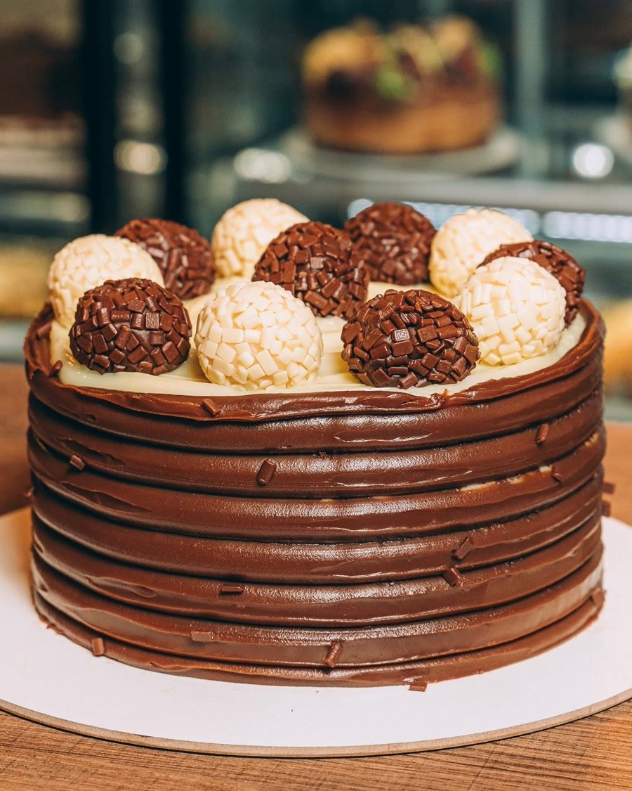 Bolo coberto de brigadeiros brancos e de chocolate da confeitaria Marquês