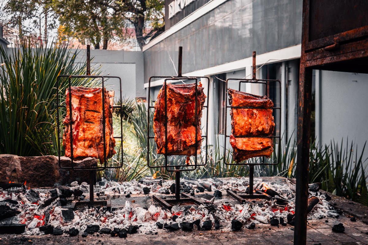 Três cruzes de carne assando lado a lado na brasa